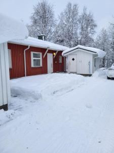 a red and white house with a snow covered driveway at Rivitaloasunto Kittilässä in Kittilä