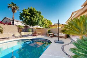 a swimming pool in a backyard with a table and chairs at Desert Sanctuary in Litchfield Park