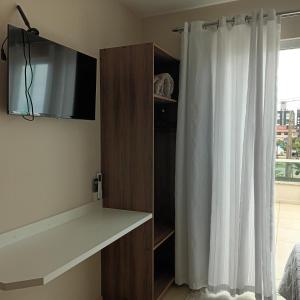 a bedroom with a tv and a white curtain at Pousada Souza & Souza in Barra Velha