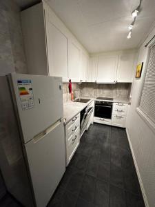 a kitchen with white cabinets and a white refrigerator at Apartment in Astrup’s Kingdom in Vassenden