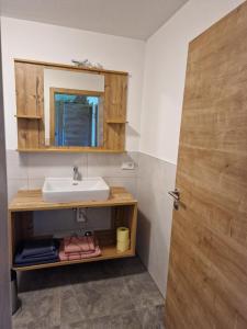 een badkamer met een wastafel en een houten deur bij Gern Mountain Living Ferienhaus Deutschmann in Sankt Johann im Pongau