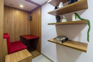 einen roten Stuhl in einem Zimmer mit Holzregalen in der Unterkunft 360 Praça da Árvore in São Paulo