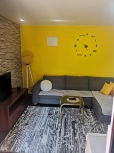 ein Wohnzimmer mit einem Sofa und einer Uhr an der Wand in der Unterkunft Sunshine apartment near the zoo, free parking in Sarajevo