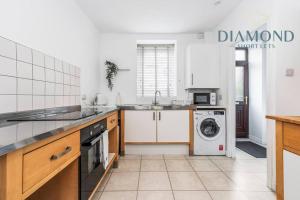 una cocina con lavadora y secadora. en FOUNDRY - 2 Bedrooms, Fully Equipped, Free Parking, WiFi, FAVOURITE for Contractors, Long Stays Welcome, Food, Bars, Shops by Diamond Short Lets, en Dunfermline