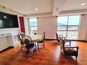 a dining room with a table and chairs and a television at apartamento con vista volcán in Pasto