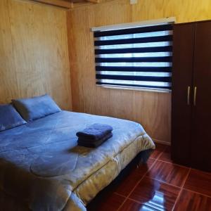 - une chambre avec un lit bleu et une fenêtre dans l'établissement Cabañas rio Biobio, à Callaqui