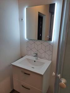 La salle de bains blanche est pourvue d'un lavabo et d'un miroir. dans l'établissement Joli Studio proche funiculaire, à Bourg-Saint-Maurice