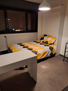 een slaapkamer met een bed met een gele en zwarte deken bij Joli Studio proche funiculaire in Bourg-Saint-Maurice