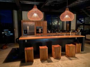 a kitchen with a bar with stools and lights at Casa Balam in Placencia Village