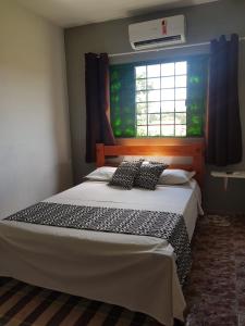 um quarto com uma cama grande e uma janela em Pouso Tião da Morena em Pirenópolis