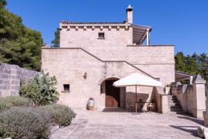 a stone building with an umbrella and a patio at Masseria Caliani in Borgagne