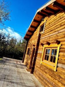 a log cabin with a yellow window and a deck at Chalet Amoureux (Région Durbuy) in Heure