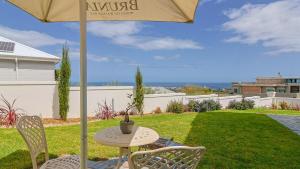 a table and chairs under an umbrella on a lawn at The View, Apartment, with magnificent sea view in Hermanus +2 photos