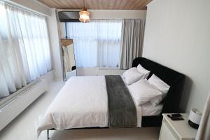 - une chambre avec un lit doté de draps blancs et une fenêtre dans l'établissement Modern Downtown apartment + FREE parking, à Larissa