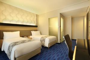 Postel nebo postele na pokoji v ubytování AI Hotel Jakarta Thamrin