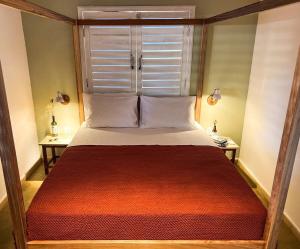 um quarto com uma cama grande e um cobertor vermelho em Casa Sapoti - 3 Suítes no centro em Pipa