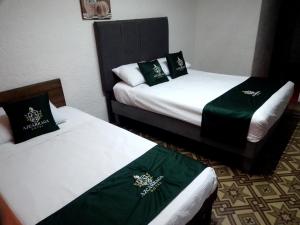 - 2 lits dans une chambre avec des draps verts et blancs dans l'établissement Hotel Don Pedro, à Puebla