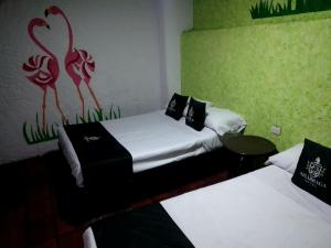 Cette chambre comprend deux lits et un tableau mural. dans l'établissement Hotel Don Pedro, à Puebla