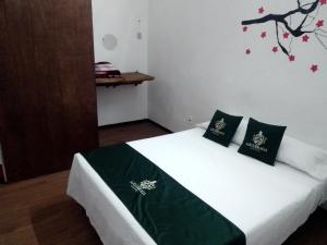 a bedroom with a white bed with black pillows at Hotel Don Pedro in Puebla