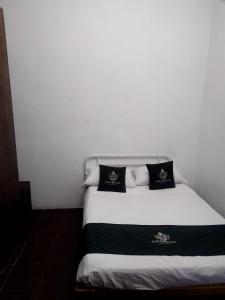 a bed with black and white pillows on it at Hotel Don Pedro in Puebla