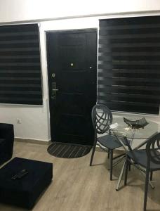 a living room with a glass table and a black door at Lovely 1-bedroom rental unit for short stays. in Tema