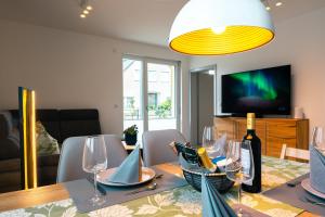 une salle à manger avec une table, des verres à vin et une télévision dans l'établissement Luxuswohnung am Steinhuder Meer - Tierfreundlich - A, à Wunstorf