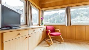 a living room with a tv and a red chair at Apartments Villa Alpina in Santa Cristina in Val Gardena