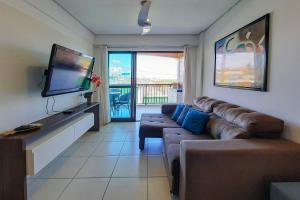 a living room with a couch and a flat screen tv at Beverly Hills 2 Suítes Apto Completo 500m Praia in Aquiraz