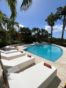 a swimming pool with white lounge chairs and a swimming pool at Residence AU 'TI SUCRIER in Deshaies