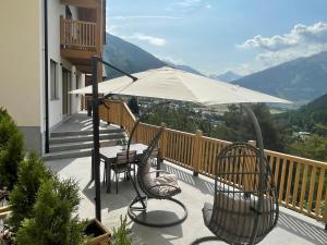 a balcony with a table and chairs and an umbrella at I Ciliegi del Conte in Bormio