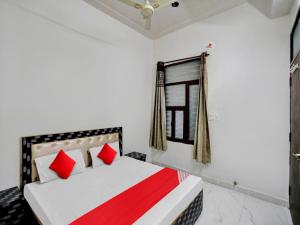 a bedroom with a bed with red pillows and a window at OYO Flagship Hotel Royal Choice in Rohtak