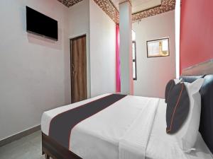 a bedroom with a bed and a tv on the wall at Collection O 81112 Hotel Joyous in Ghaziabad