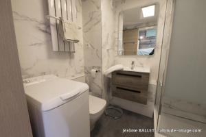 a white bathroom with a toilet and a sink at NID DOUILLET DE FLAINE in Flaine