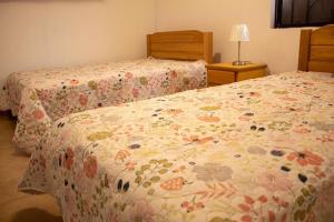 a bedroom with two beds with a floral comforter at Amplia Casa de Campo con Piscina en Cieneguilla in Cieneguilla