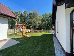 een achtertuin met een speeltuin en een schommel bij Domek na skraju lasu in Uniejow