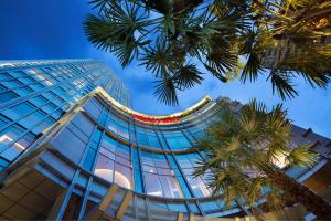een hoog gebouw met een palmboom ervoor bij Bangkok Marriott Hotel Sukhumvit in Bangkok