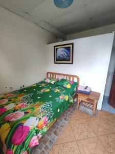 a bedroom with a bed with a green comforter and a table at Hotel Maeo in Montañita