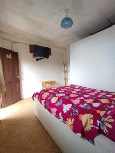 a bedroom with a bed with a red blanket with flowers at Hotel Maeo in Montañita