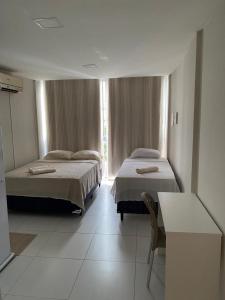 a bedroom with two beds and a window at Pousada Terra Bela in Juazeiro do Norte