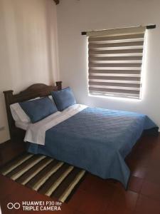 a bedroom with a bed with blue sheets and a window at Casa Donde Gomez in Villa de Leyva