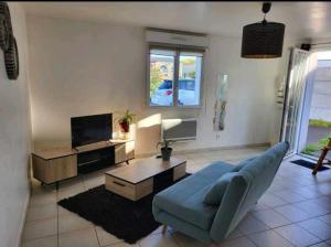 a living room with a blue couch and a tv at Appartement camon in Camon