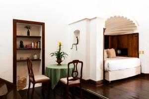 a bedroom with a bed and a table and chairs at Posada del Tepozteco - Hotel & Gallery in Tepoztlán