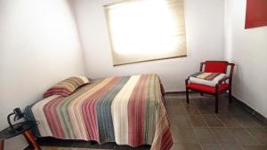 a bedroom with a bed and a red chair at Loft em Souzas in Joaquim Egídio