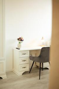 a white desk with a chair and a vase of flowers at Kasa Nouveau in Oradea