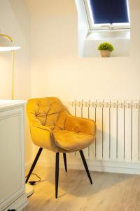 a yellow chair sitting in a room with a window at Kasa Nouveau in Oradea