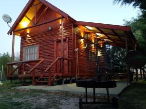 eine Holzhütte mit einer Veranda und einer Schaukel in der Unterkunft La Mora Cabañas in Villa Urquiza
