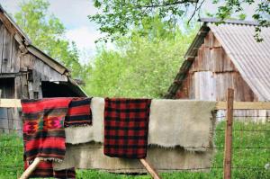 a blanket hanging on a fence next to a barn at Domacinstvo na kraju svijeta in Šipovo