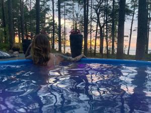 a woman sitting in a hot tub with the sunset at Pie jūras in Klapkalnciems