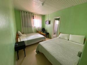 a green room with two beds and a window at Pousada355 in Passo Fundo