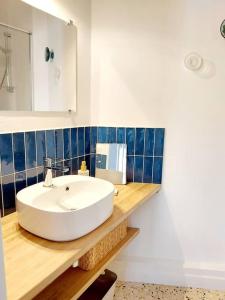 ein Badezimmer mit einem weißen Waschbecken und einem Spiegel in der Unterkunft Le Moth Marseillan in Marseillan